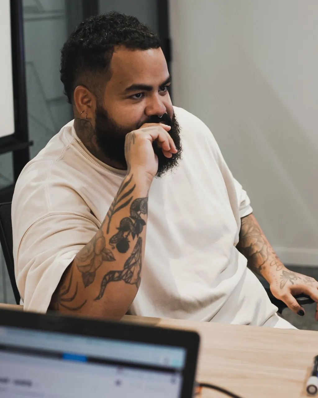 Lucas, social media da Detalhe, de mão no queixo na reunião de planejamento