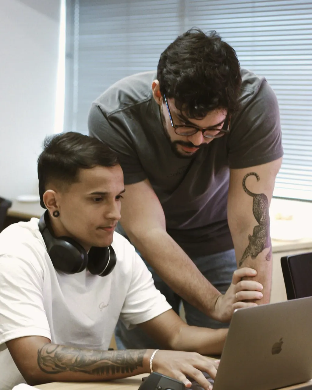 Igor, em pé, acompanha o designer Web montando uma página no notebook