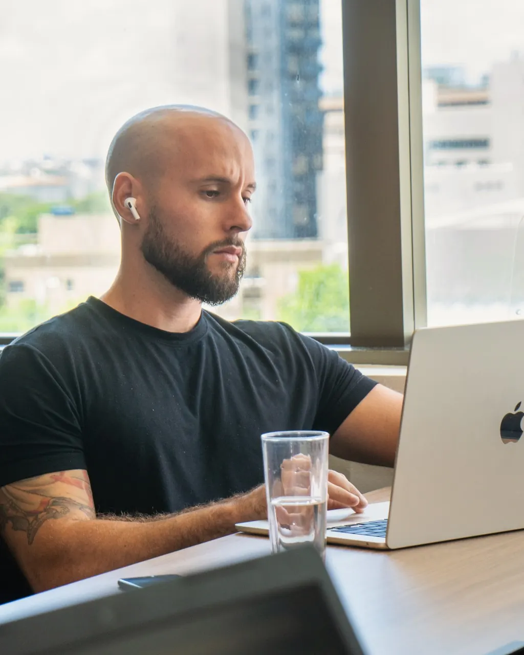 Vinícius, de fone, atendendo pelo notebook na mesa perto da janela